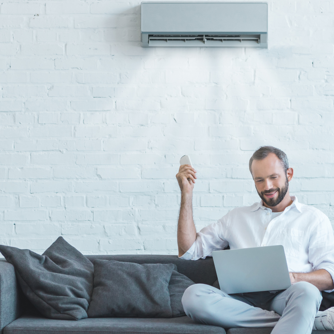 man sitting in home beneath ac unit